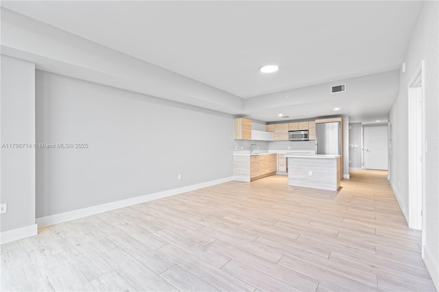16385 Biscayne Blvd Unit 404, North Miami Beach, FL 33160 - kitchen with stainless steel microwave, light countertops, light brown cabinetry, baseboards, and recessed lighting