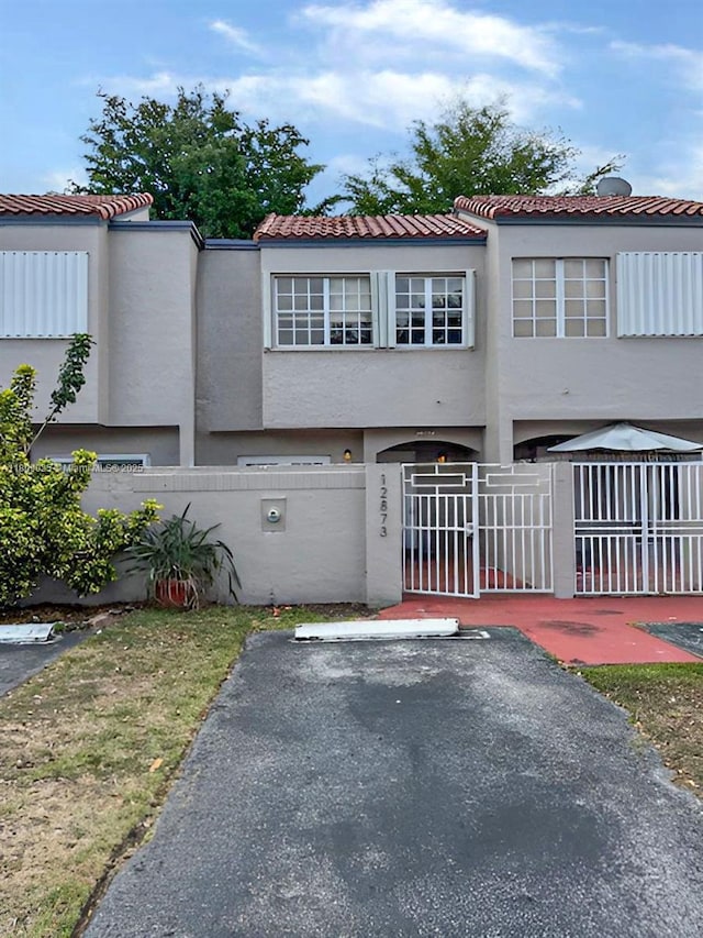 12873 SW 65th Ter, Miami, FL 33183 - view of front facade featuring stucco siding, a fenced front yard, a gate, and a tiled roof