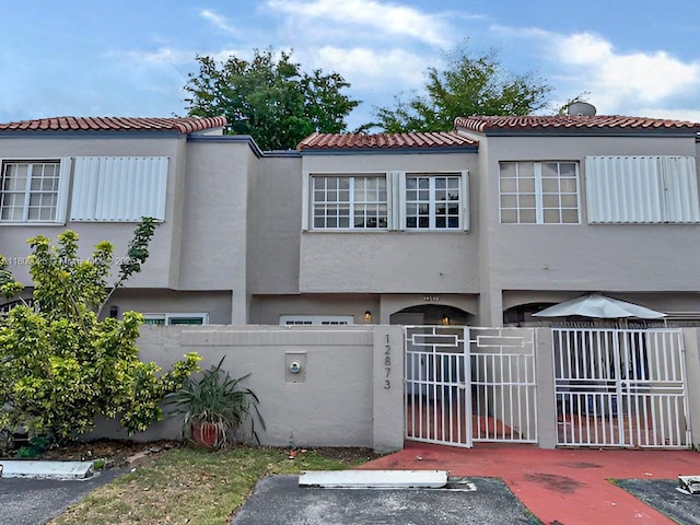 12873 SW 65th Ter, Miami, FL 33183 - view of front of home featuring a fenced front yard, a gate, stucco siding, and a tiled roof