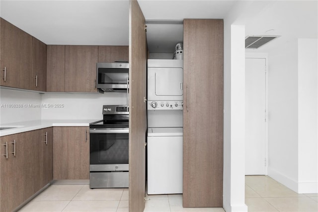 1901 Brickell Ave Unit B1903, Miami, FL 33129 - kitchen featuring stainless steel appliances, stacked washer and clothes dryer, light countertops, light tile patterned flooring, and dark brown cabinets
