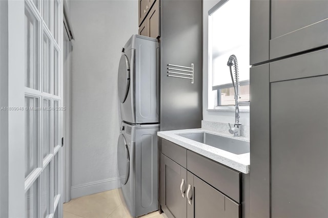 4231 N Magnolia Cir, Delray Beach, FL 33445 - laundry room featuring stacked washing machine and dryer, cabinet space, light tile patterned flooring, and baseboards