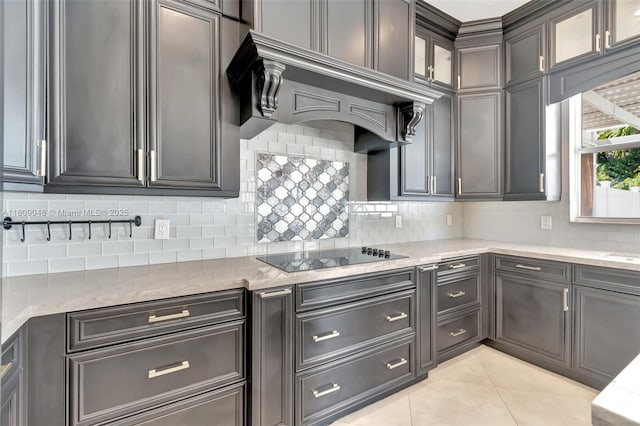 4231 N Magnolia Cir, Delray Beach, FL 33445 - kitchen with black electric cooktop, light tile patterned flooring, backsplash, glass insert cabinets, and light stone counters