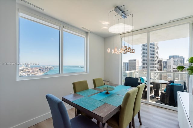 244 Biscayne Blvd Unit 3703, Miami, FL 33132 - dining room with light wood-style floors, a view of city, a chandelier, and baseboards