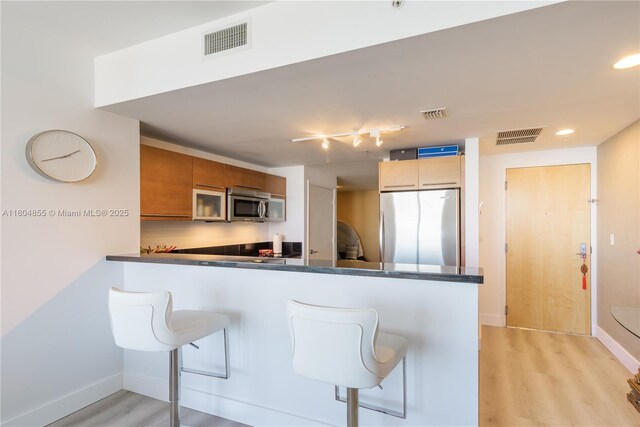 244 Biscayne Blvd Unit 3703, Miami, FL 33132 - kitchen featuring appliances with stainless steel finishes, dark countertops, light wood-style floors, a kitchen bar, and recessed lighting