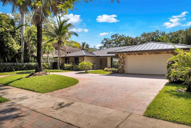 3721 N Park Rd, Hollywood, FL 33021 - view of front facade featuring curved driveway, a standing seam roof, an attached garage, stone siding, and a front yard