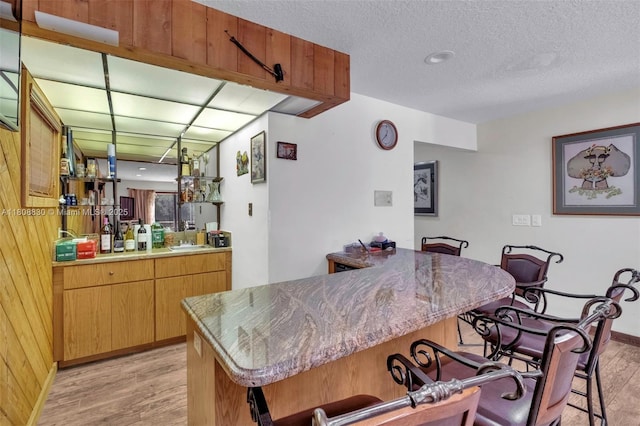 3721 N Park Rd, Hollywood, FL 33021 - kitchen with light wood finished floors, a kitchen breakfast bar, a textured ceiling, and baseboards