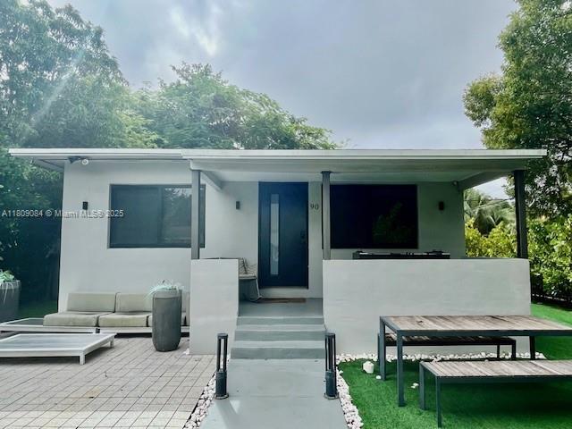 90 NW 33rd St, Miami, FL 33127 - rear view of property with stucco siding, a patio, and an outdoor living space
