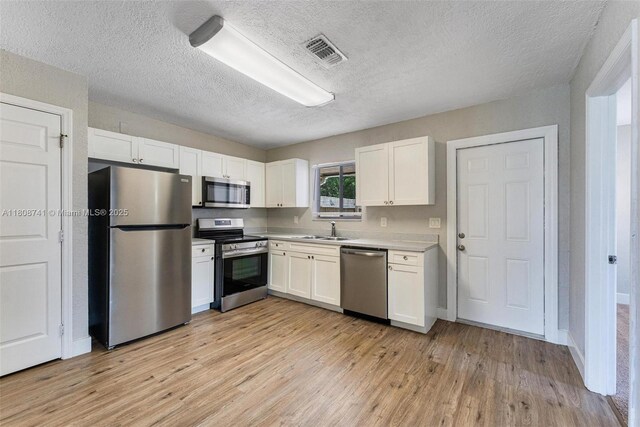 22123 SW 62nd Ct, Boca Raton, FL 33428 - kitchen with stainless steel appliances, a sink, light wood-style flooring, white cabinets, and light countertops