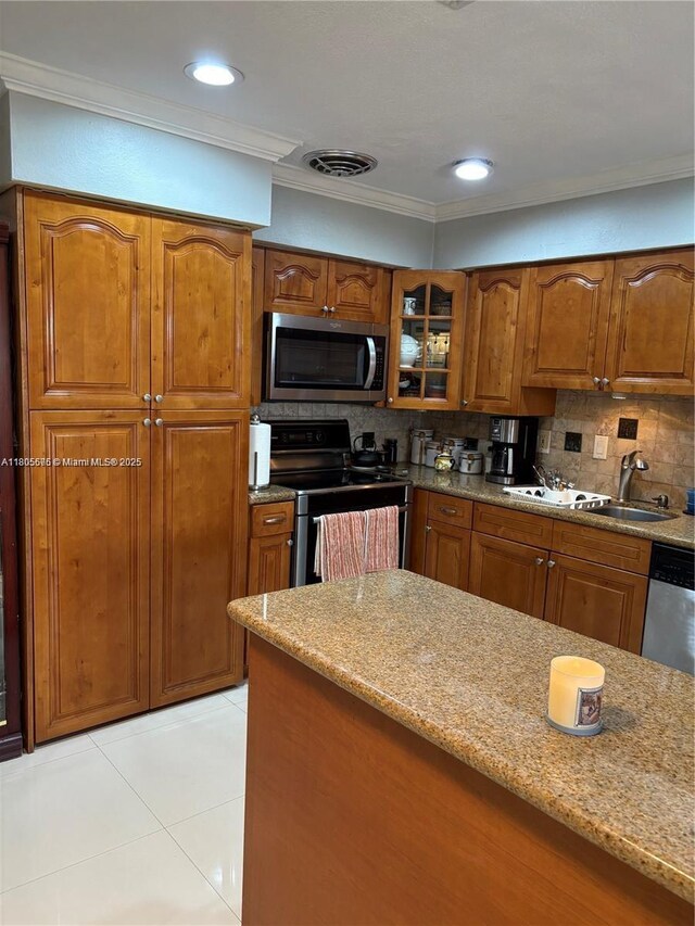 7430 Buchanan St, Hollywood, FL 33024 - kitchen featuring stainless steel appliances, crown molding, brown cabinets, light tile patterned floors, and backsplash