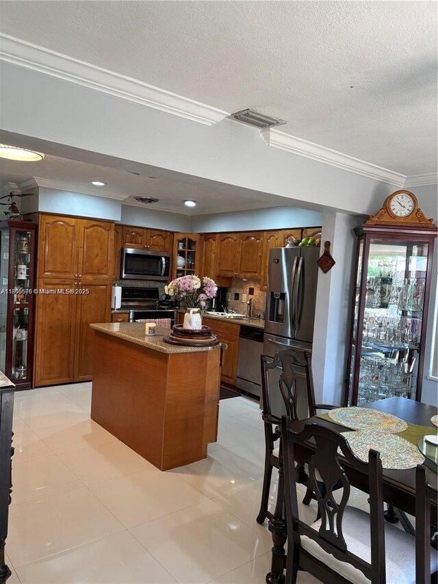 7430 Buchanan St, Hollywood, FL 33024 - kitchen with appliances with stainless steel finishes, brown cabinets, glass insert cabinets, tasteful backsplash, and crown molding