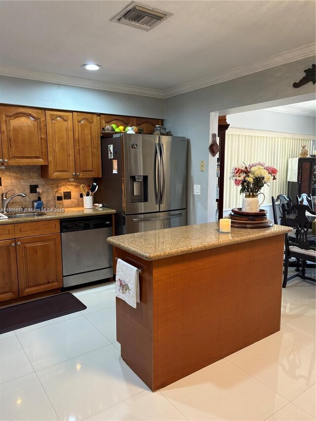7430 Buchanan St, Hollywood, FL 33024 - kitchen with stainless steel appliances, a center island, brown cabinets, crown molding, and tasteful backsplash