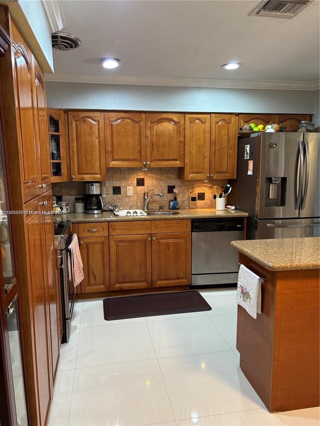 7430 Buchanan St, Hollywood, FL 33024 - kitchen featuring appliances with stainless steel finishes, crown molding, brown cabinets, a kitchen island, and a textured ceiling