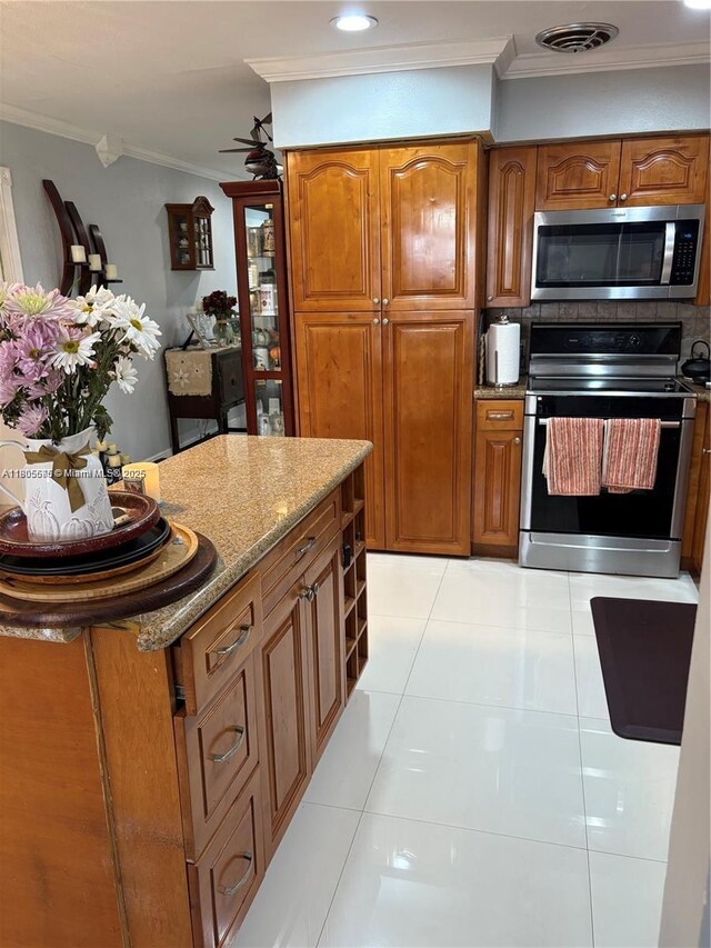 7430 Buchanan St, Hollywood, FL 33024 - kitchen with appliances with stainless steel finishes, crown molding, brown cabinetry, light stone countertops, and light tile patterned floors