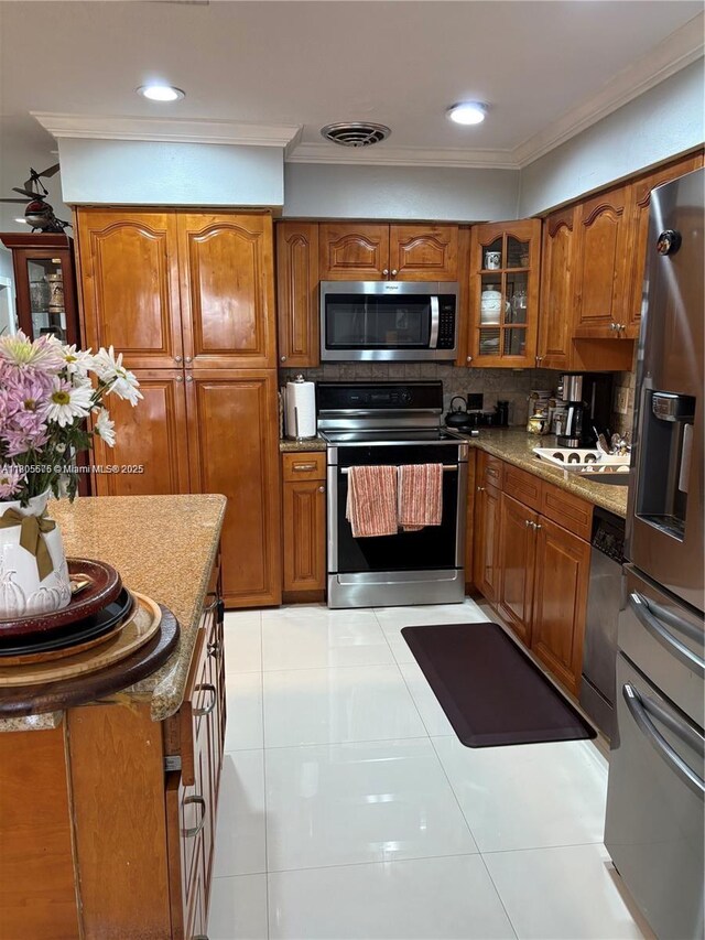 7430 Buchanan St, Hollywood, FL 33024 - kitchen with stainless steel appliances, a center island, brown cabinets, crown molding, and tasteful backsplash