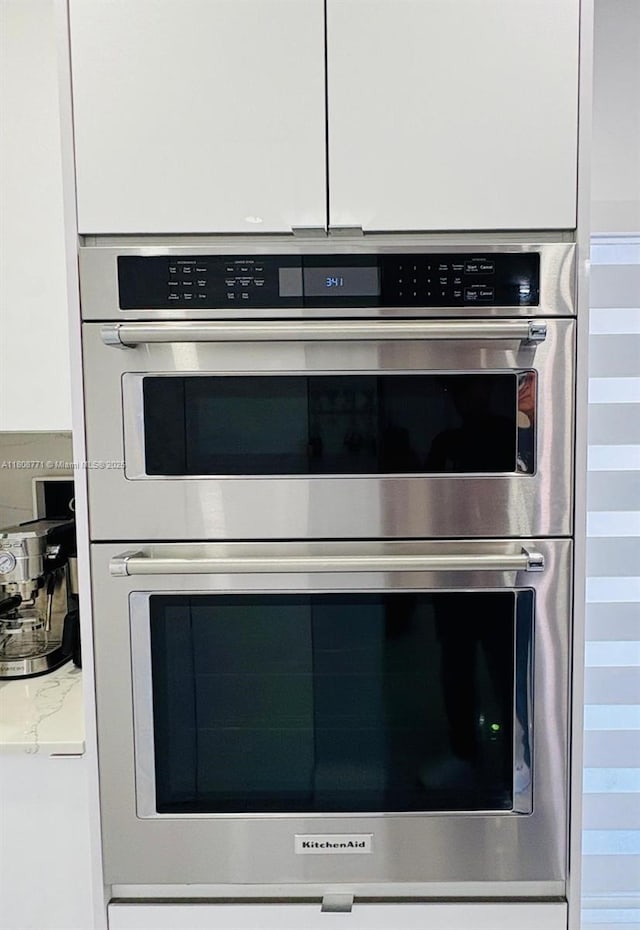 13729 SW 171st Ln, Miami, FL 33177 - kitchen view of stainless steel double oven, white cabinetry, and light stone countertops