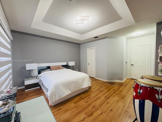 13729 SW 171st Ln, Miami, FL 33177 - bedroom featuring a tray ceiling, light wood-style floors, baseboards, and a textured ceiling
