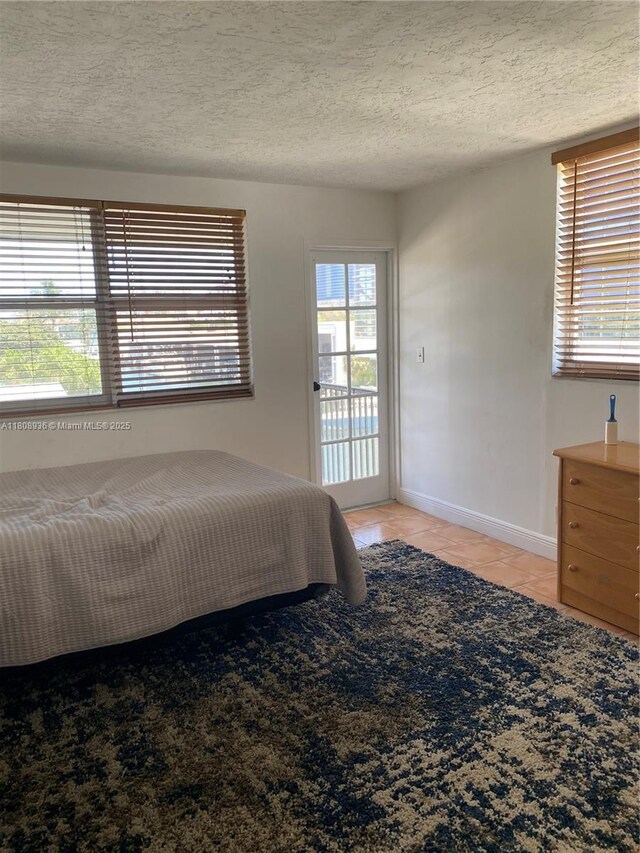 1424 SE 15th St Unit 45, Fort Lauderdale, FL 33316 - bedroom featuring access to outside, light tile patterned floors, a textured ceiling, and baseboards