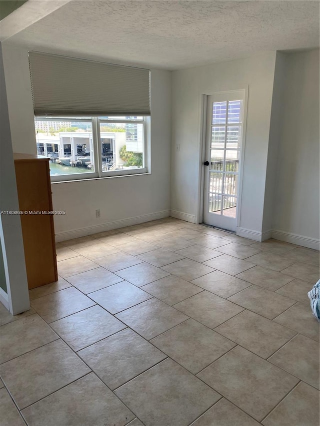 1424 SE 15th St Unit 45, Fort Lauderdale, FL 33316 - empty room featuring a textured ceiling, light tile patterned floors, and baseboards