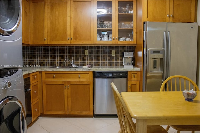 1865 Brickell Ave Unit A2111, Miami, FL 33129 - kitchen with stainless steel appliances, stacked washing machine and dryer, a sink, brown cabinetry, and backsplash