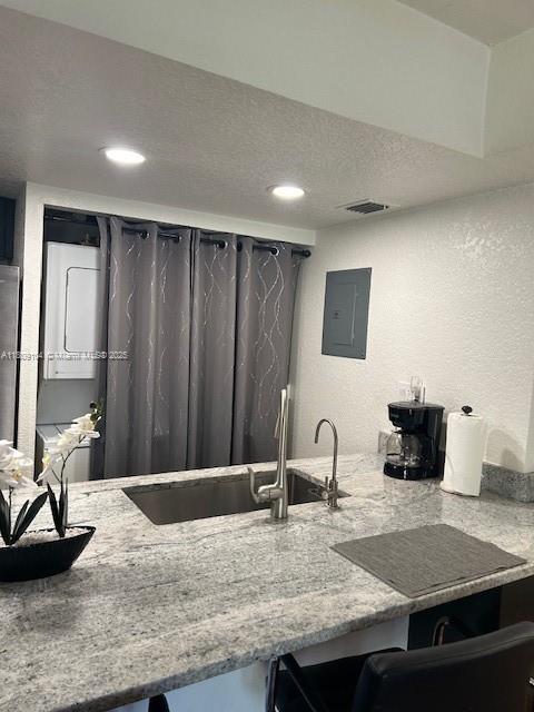 5326 NE 6th Ave Unit E23, Oakland Park, FL 33334 - kitchen featuring electric panel, a textured wall, light stone counters, recessed lighting, and a sink