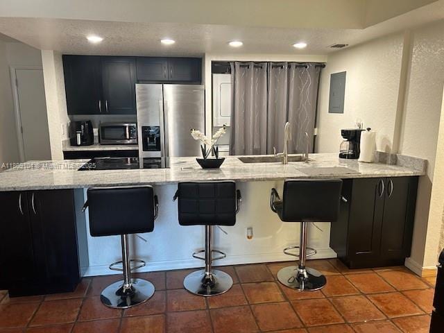 5326 NE 6th Ave Unit E23, Oakland Park, FL 33334 - kitchen with stainless steel appliances, a breakfast bar area, a sink, light stone countertops, and dark cabinetry