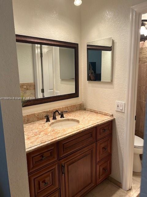 5326 NE 6th Ave Unit E23, Oakland Park, FL 33334 - full bathroom featuring toilet, vanity, tile patterned floors, and a textured wall