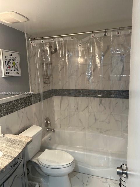 5326 NE 6th Ave Unit E23, Oakland Park, FL 33334 - bathroom with marble look tile flooring, toilet, shower / tub combo with curtain, vanity, and tile walls