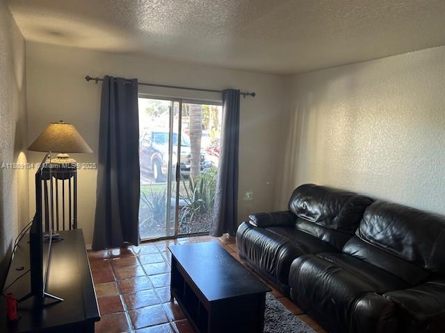 5326 NE 6th Ave Unit E23, Oakland Park, FL 33334 - living room featuring a textured ceiling and dark tile patterned flooring