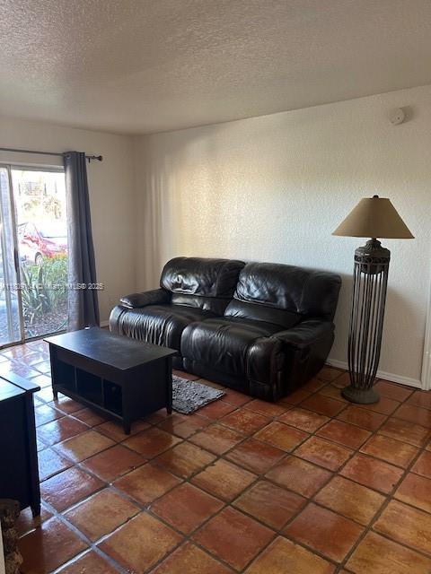 5326 NE 6th Ave Unit E23, Oakland Park, FL 33334 - living area featuring a textured ceiling, tile patterned floors, and baseboards