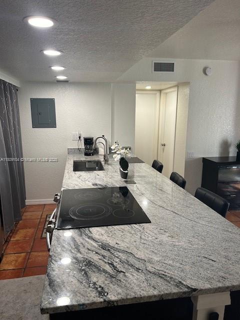 5326 NE 6th Ave Unit E23, Oakland Park, FL 33334 - kitchen with a breakfast bar, a sink, electric panel, electric range, and light stone counters