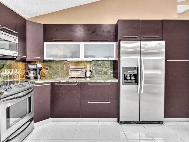457 Cambridge Dr, Weston, FL 33326 - kitchen with appliances with stainless steel finishes, lofted ceiling, light stone counters, and backsplash