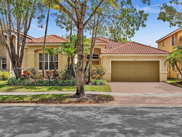 457 Cambridge Dr, Weston, FL 33326 - mediterranean / spanish home featuring stucco siding, a tiled roof, an attached garage, and decorative driveway