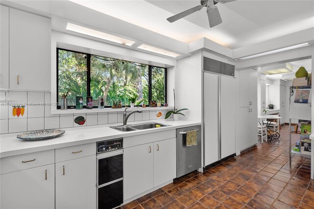 5465 Banyan Trl, Coral Gables, FL 33156 - kitchen with stainless steel dishwasher, a sink, light countertops, and tasteful backsplash