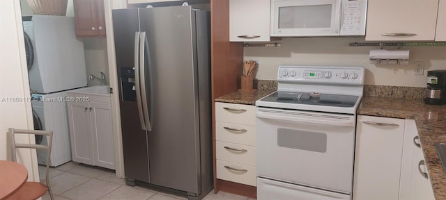 18100 N Bay Rd Unit Ph7, Sunny Isles Beach, FL 33160 - kitchen featuring white appliances, stacked washer / drying machine, light tile patterned flooring, and dark stone countertops
