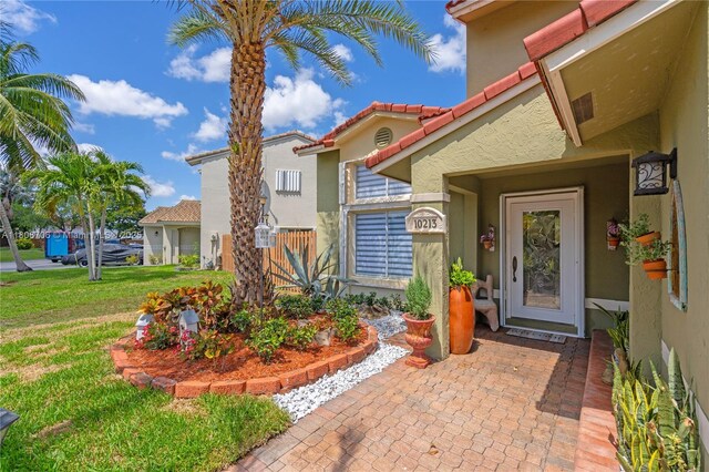 10213 SW 156th Ave, Miami, FL 33196 - view of exterior entry featuring stucco siding, a lawn, and a tile roof