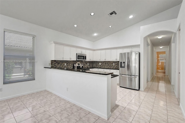 11564 Puerto Blvd, Boynton Beach, FL 33437 - kitchen featuring stainless steel appliances, vaulted ceiling, dark countertops, a peninsula, and arched walkways
