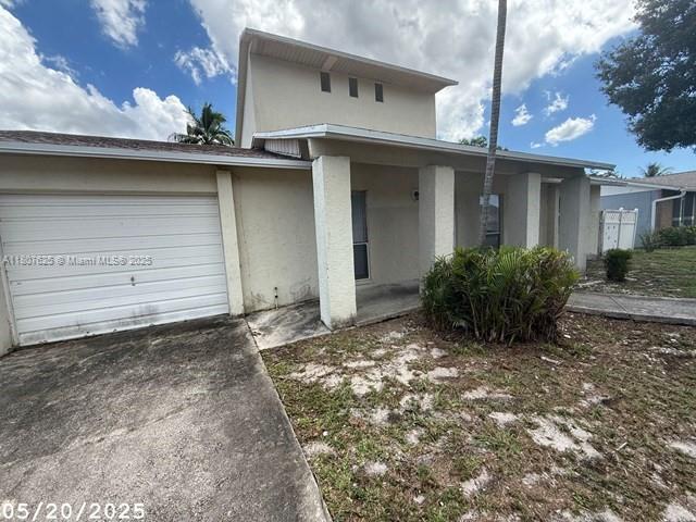 6160 Camp Lee Rd, West Palm Beach, FL 33417 - view of front facade with driveway, an attached garage, and stucco siding