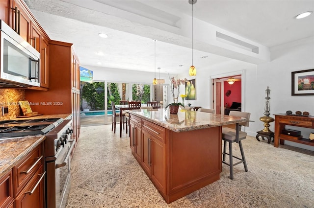 1771 Wa Kee Na Dr, Miami, FL 33133 - kitchen with appliances with stainless steel finishes, a kitchen bar, light stone countertops, a kitchen island, and recessed lighting