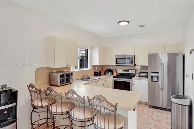 5972 SW 163rd Pl, Miami, FL 33193 - kitchen with appliances with stainless steel finishes, a peninsula, light countertops, cream cabinetry, and a kitchen bar