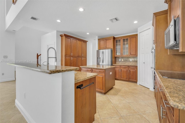 5466 SW 187th Ter, Miramar, FL 33029 - kitchen with stainless steel appliances, a center island with sink, brown cabinetry, and recessed lighting