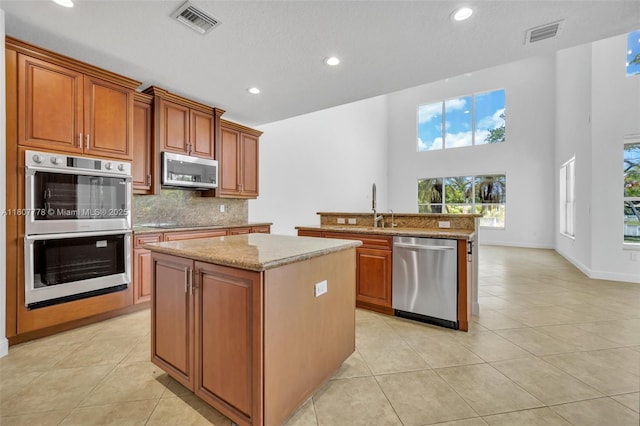 5466 SW 187th Ter, Miramar, FL 33029 - kitchen with appliances with stainless steel finishes, a center island, light tile patterned floors, decorative backsplash, and recessed lighting