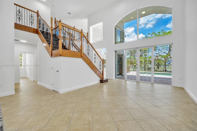 5466 SW 187th Ter, Miramar, FL 33029 - unfurnished living room with a towering ceiling, light tile patterned floors, baseboards, stairs, and recessed lighting