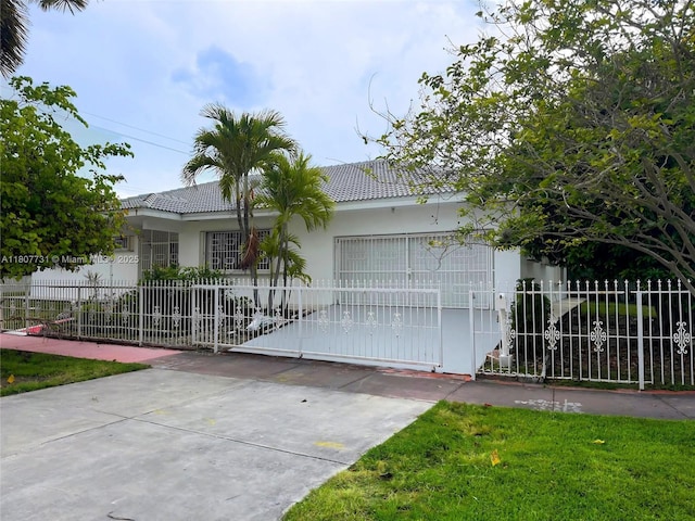 1500 71st St, Miami Beach, FL 33141 - ranch-style home with a tiled roof, a fenced front yard, stucco siding, and a gate