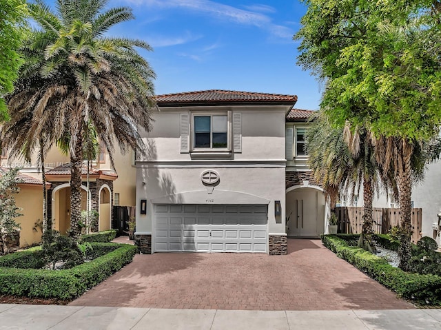 4362 NW 112th Ct, Doral, FL 33178 - mediterranean / spanish-style house featuring stone siding, decorative driveway, a tile roof, stucco siding, and a garage
