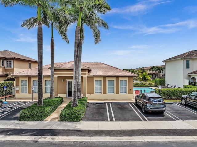 4362 NW 112th Ct, Doral, FL 33178 - view of front of property with a tile roof, stucco siding, uncovered parking, and a swimming pool
