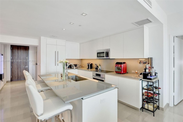 68 SE 6th St Unit 1203, Miami, FL 33131 - kitchen with stainless steel appliances, a sink, modern cabinets, a kitchen breakfast bar, and white cabinets