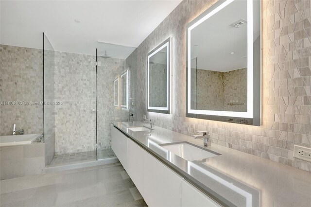 68 SE 6th St Unit 1203, Miami, FL 33131 - full bathroom with double vanity, a tile shower, a bath, tile walls, and tasteful backsplash