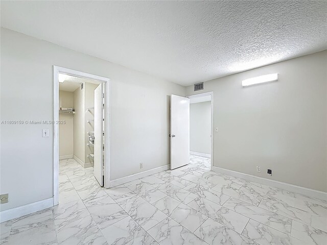 1100 SW 130th Ave Unit 111H, Pembroke Pines, FL 33027 - unfurnished bedroom with light marble finish floors, baseboards, a spacious closet, and a textured ceiling