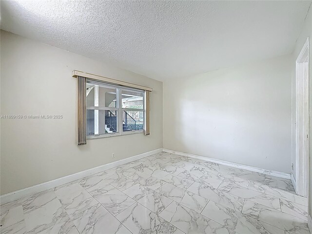 1100 SW 130th Ave Unit 111H, Pembroke Pines, FL 33027 - spare room featuring baseboards, marble finish flooring, and a textured ceiling