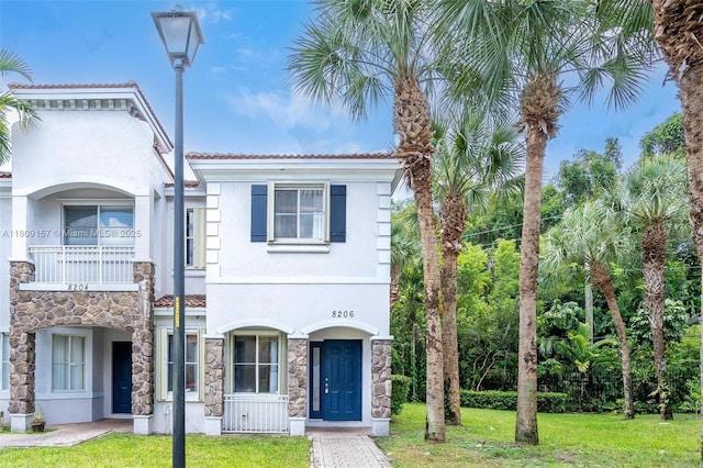 8206 SW 29th St Unit 104, Miramar, FL 33025 - view of front of home featuring a front yard, stucco siding, a balcony, and stone siding